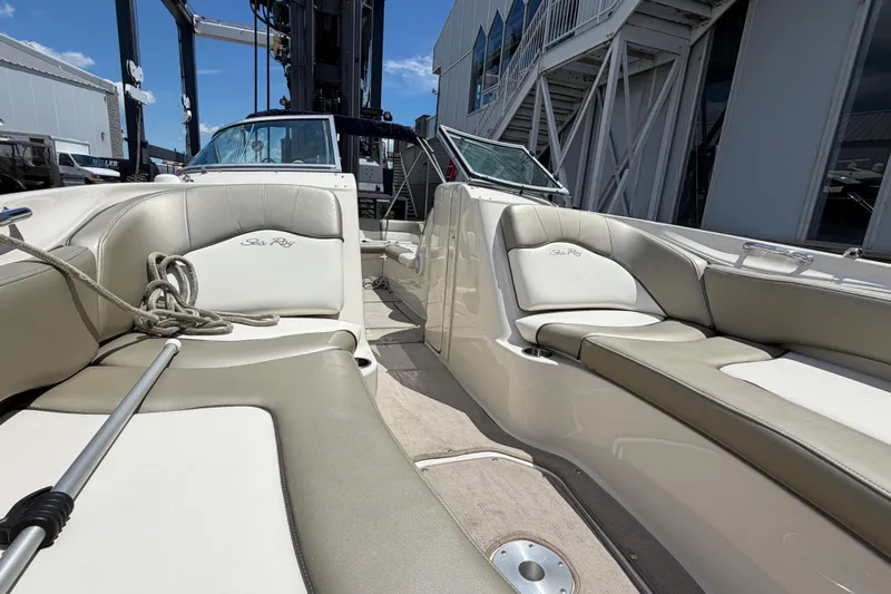 Slide: The Image of 2004 Sea Ray 240 Sundeck interior with beige seating, docked near a marina. - 29