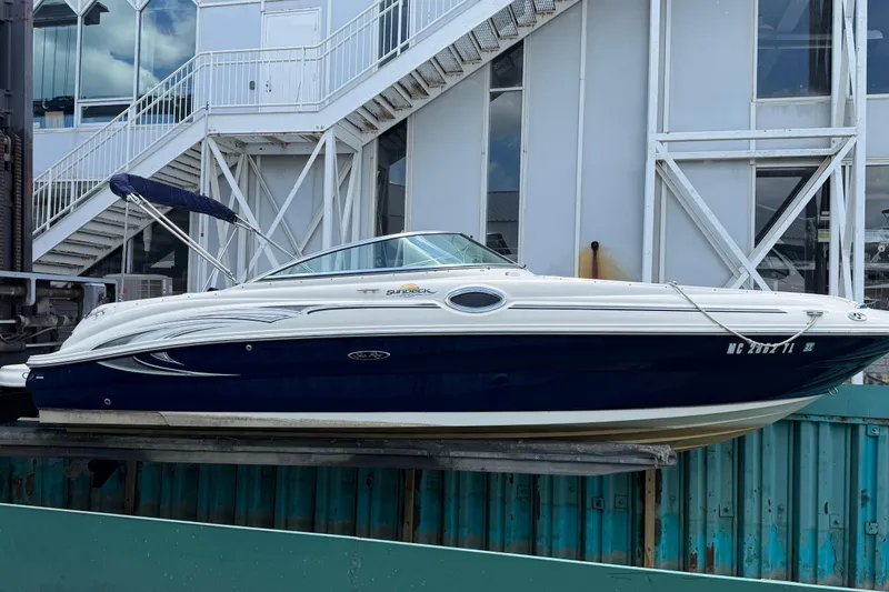 Slide: The Image of 2004 Sea Ray 240 Sundeck boat docked near industrial building. - 4