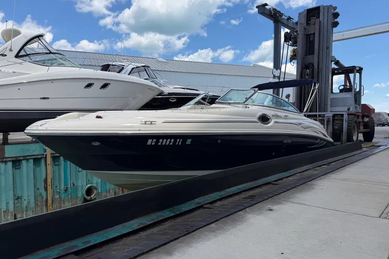 Slide: The Image of 2004 Sea Ray 240 Sundeck boat on a lift at a marina under a blue sky. - 6