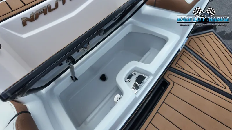 Slide: The Image of The image shows a storage compartment on a 2022 Nautique G25 boat with wood accents. - 39