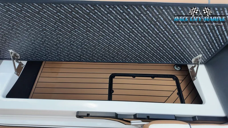 Slide: The Image of An open storage compartment on a 2022 Nautique G25 boat with wood-patterned flooring. - 18