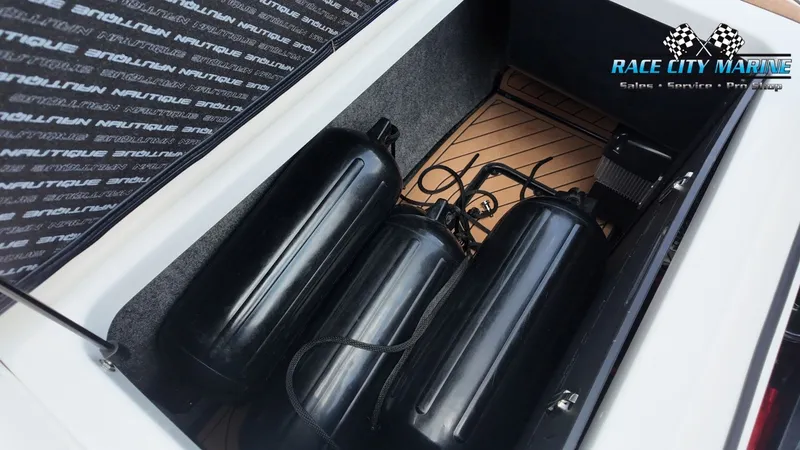 Slide: The Image of The image shows the storage compartment of a 2022 Nautique G25 boat with black fenders. - 33