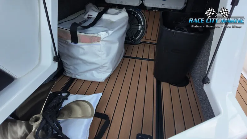 Slide: The Image of The storage area of a 2022 Nautique G25 with bags and accessories on a wooden floor. - 41