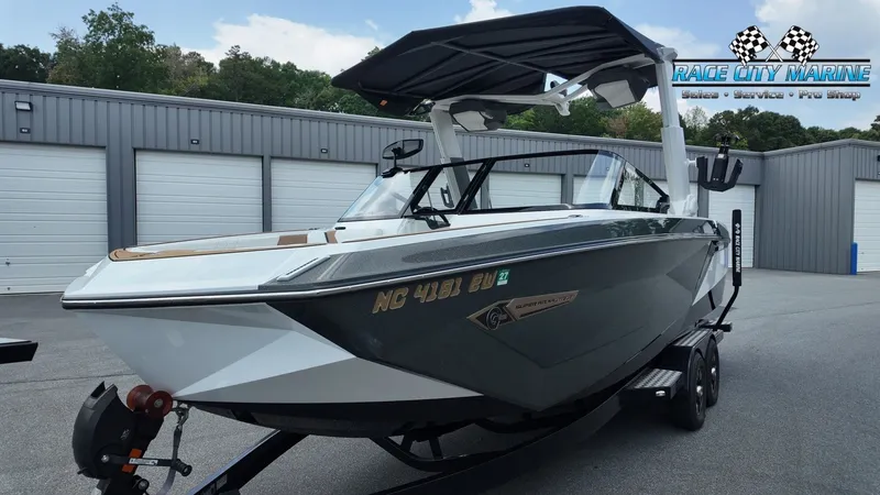 Slide: The Image of A 2022 Nautique G25 boat on a trailer in front of garages. It features a modern design. - 6