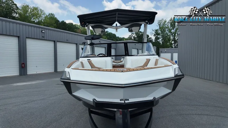 Slide: The Image of A 2022 Nautique G25 boat on a trailer in front of garages. It features a modern design. - 3