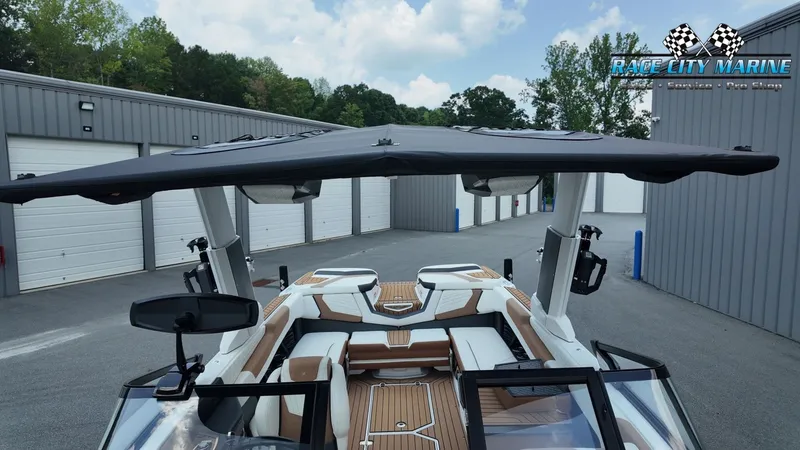 Slide: The Image of A 2022 Nautique G25 with a large sunshade, parked in front of garages. - 36