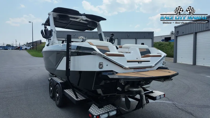 Slide: The Image of A 2022 Nautique G25 boat on a trailer, parked in a lot in front of warehouse buildings. - 7
