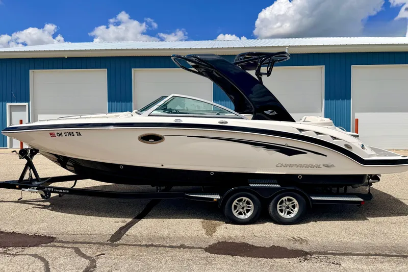Slide: The Image of 2015 Chaparral Sunesta 264 boat on trailer, parked near blue building. - 114