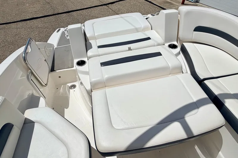 Slide: The Image of 2015 Chaparral Sunesta 264 boat interior with white cushioned seating and cup holders. - 28