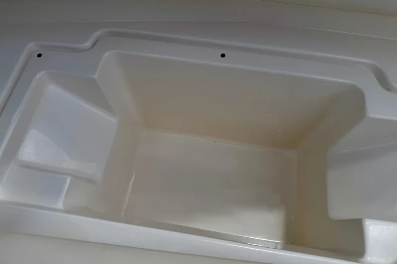 Slide: The Image of Storage compartment of a 2015 Chaparral Sunesta 264 boat, featuring a clean, white interior. - 40