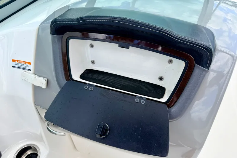 Slide: The Image of 2015 Chaparral Sunesta 264 boat storage compartment with open lid and warning label. - 55