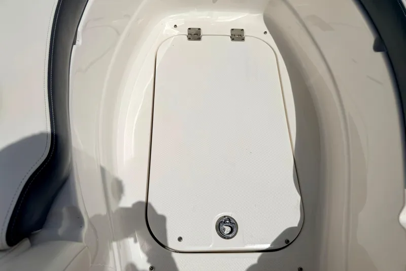Slide: The Image of 2015 Chaparral Sunesta 264 boat storage compartment with latch, white interior. - 85