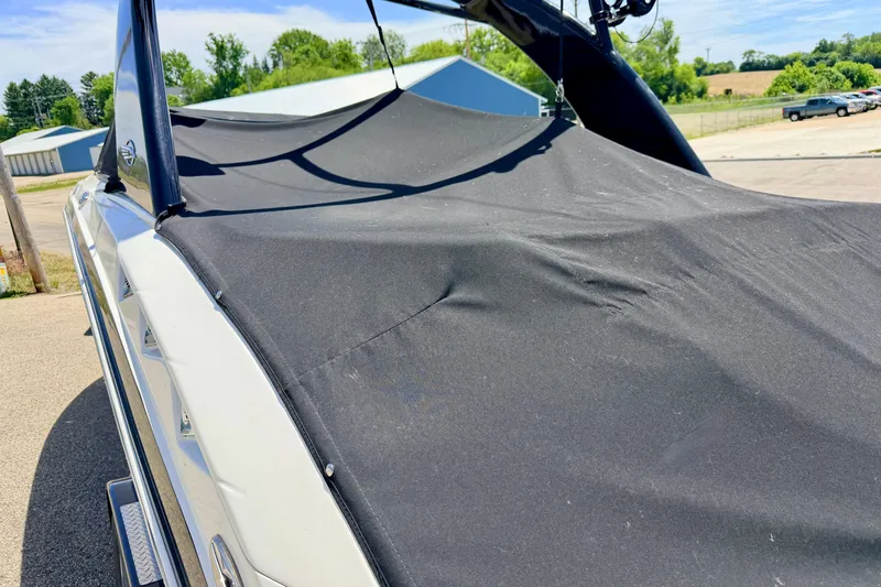 Slide: The Image of 2015 Chaparral Sunesta 264 boat with black cover in outdoor setting. - 90