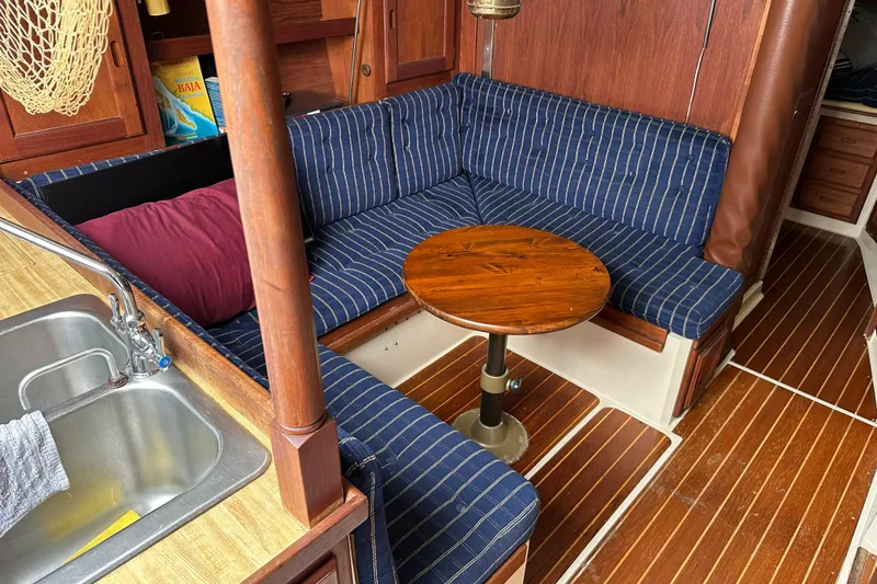 Slide: The Image of Interior of 1985 Catalina 36 sailboat with striped seating and wooden table. - 13