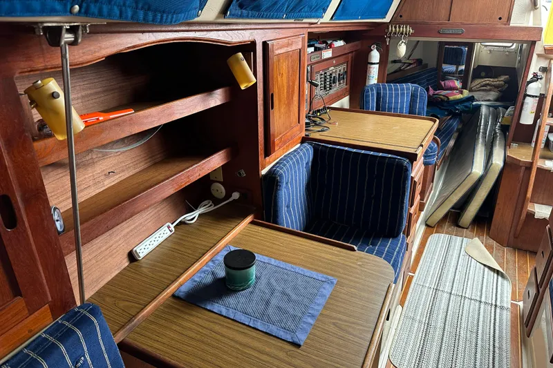 Slide: The Image of Interior of a 1985 Catalina 36 sailboat with wooden cabinetry and blue-striped seating. - 20