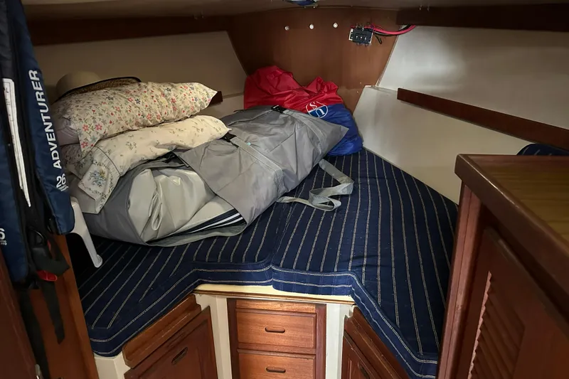 Slide: The Image of Cozy cabin interior of a 1985 Catalina 36 sailboat with striped bedding and storage. - 24