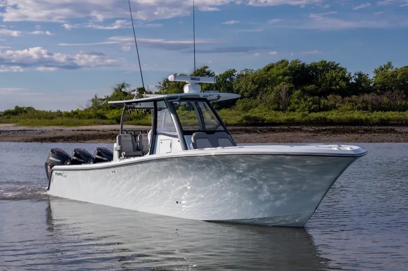 Slide: The Image of 2024 Front Runner 36 Center Console boat cruising on calm water, with lush greenery in background. - 6