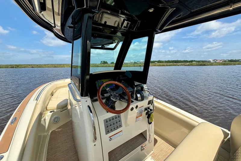 Slide: The Image of 2020 Chris-Craft Catalina 27 boat interior with steering wheel, on calm water under blue sky. - 23