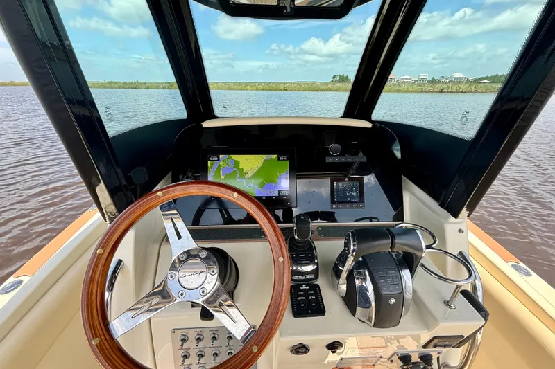 Slide: The Image of 2020 Chris-Craft Catalina 27 helm with navigation display and controls on a sunny day. - 24