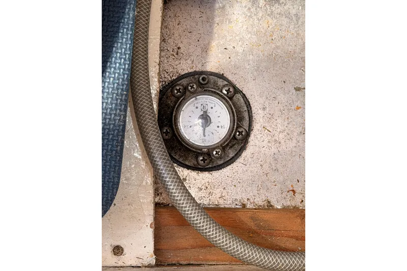 Slide: The Image of Fuel gauge on a 1991 Caliber 33 boat, surrounded by hoses and textured surfaces. - 52