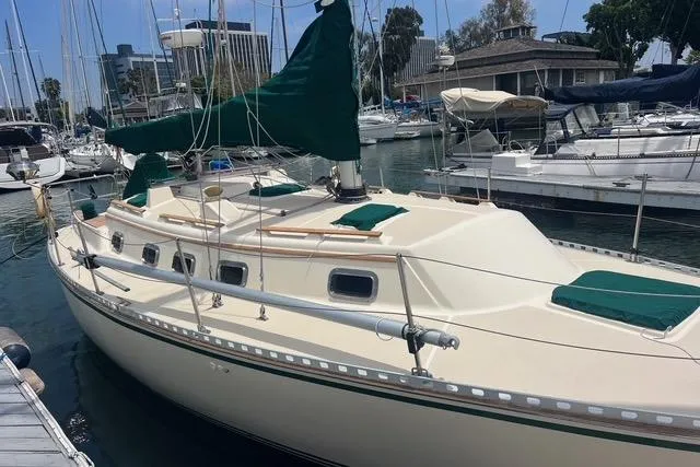 Slide: The Image of 1991 Caliber 33 sailboat docked in a marina, featuring green sail covers. - 11