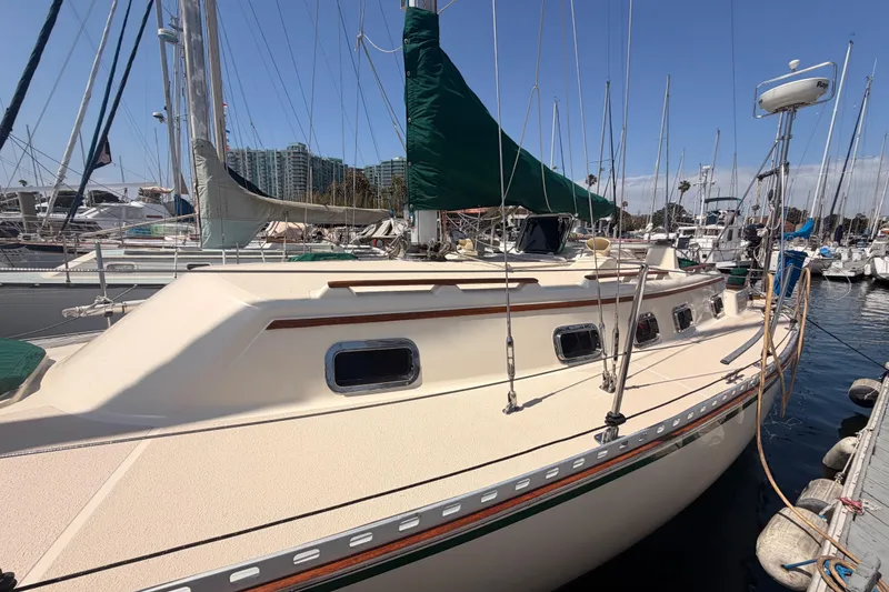 Slide: The Image of 1991 Caliber 33 sailboat docked at marina, featuring green sail cover and multiple windows. - 10