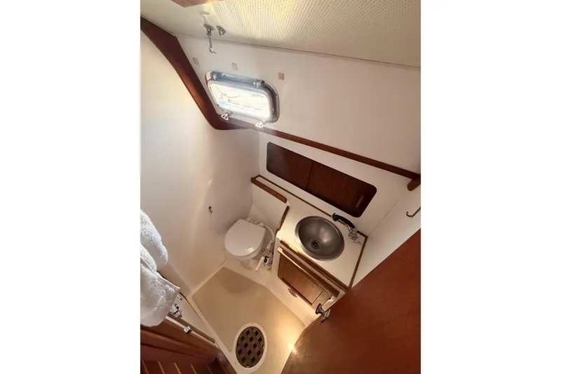 Slide: The Image of 1991 Caliber 33 yacht bathroom with toilet, sink, and porthole window. - 42