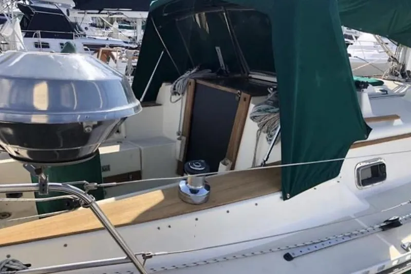 Slide: The Image of 1991 Caliber 33 sailboat with green canopy and deck equipment in marina setting. - 29