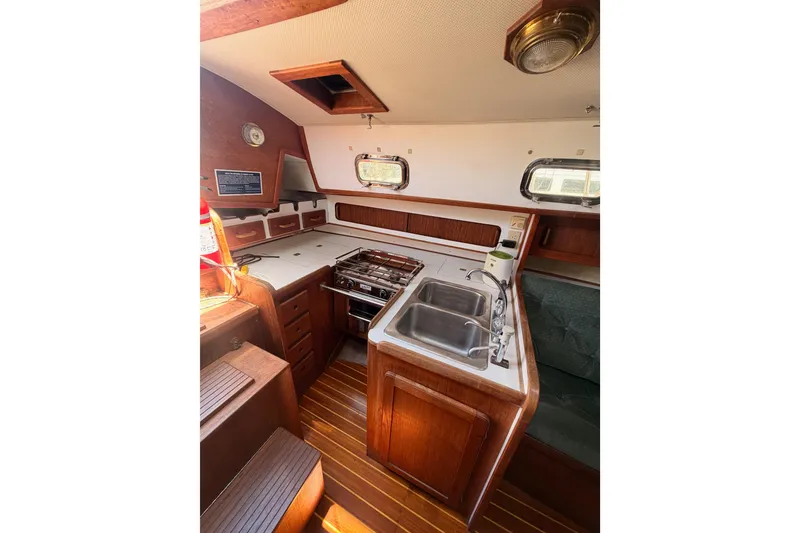 Slide: The Image of 1991 Caliber 33 yacht interior with wooden cabinetry, dual sink, and stove in the galley. - 32