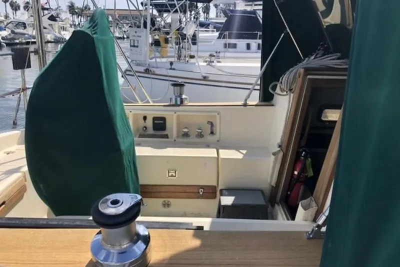 Slide: The Image of Sailboat cockpit of 1991 Caliber 33, featuring green covers and marina background. - 30