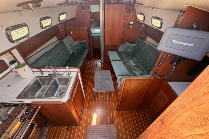 Slide: The Image of Interior of a 1991 Caliber 33 sailboat with wood finish and green seating. - 30