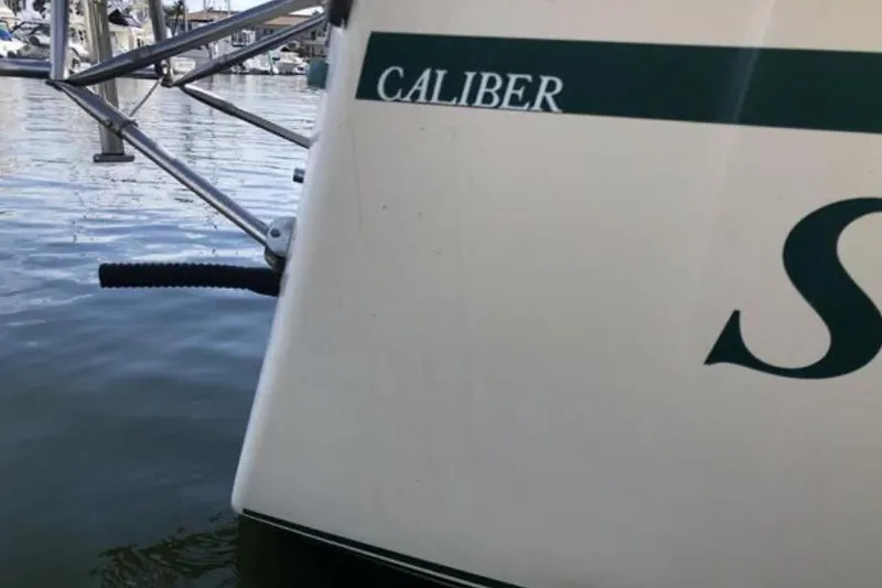 Slide: The Image of 1991 Caliber 33 sailboat docked in marina, partial view of hull and water. - 40
