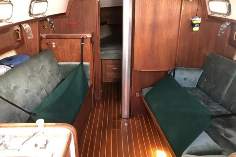Slide: The Image of Interior of a 1991 Caliber 33 sailboat with wood paneling and green seating. - 45
