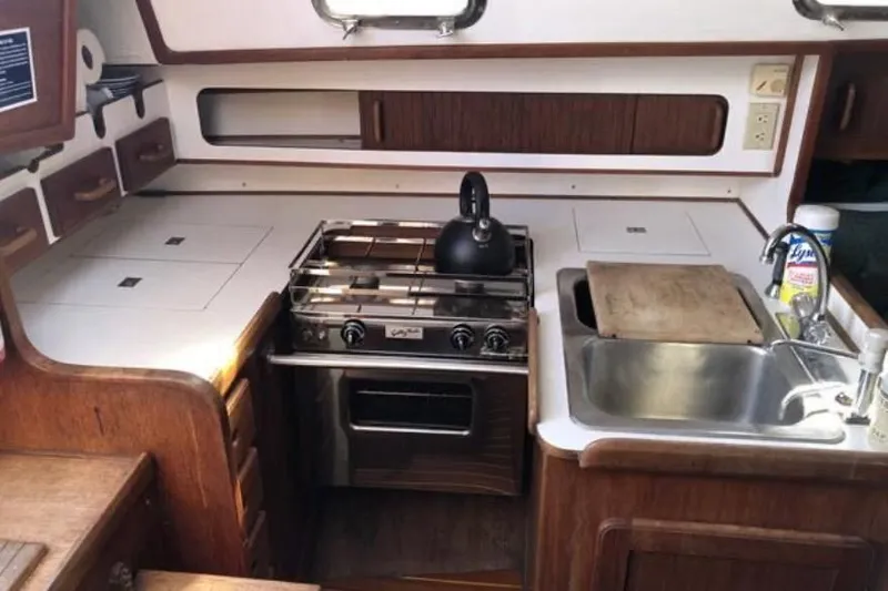 Slide: The Image of 1991 Caliber 33 yacht kitchen with stove, sink, and wooden cabinetry. - 57