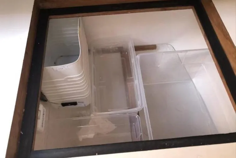 Slide: The Image of Hidden storage compartment with plastic containers in a 1991 Caliber 33 boat. - 59