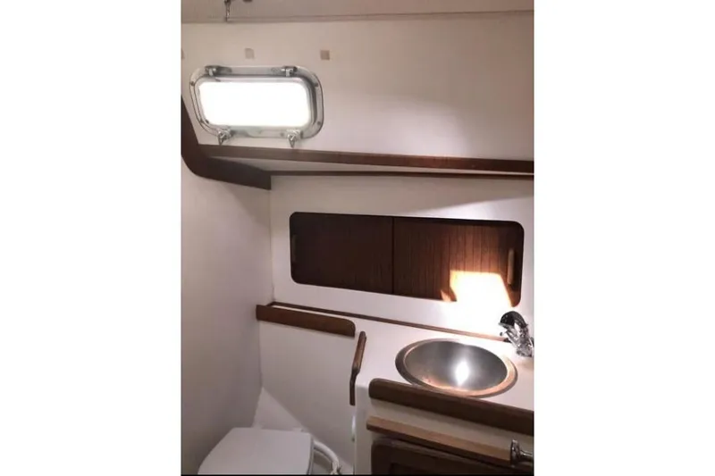 Slide: The Image of 1991 Caliber 33 yacht bathroom with sink, toilet, and wooden cabinetry. - 66