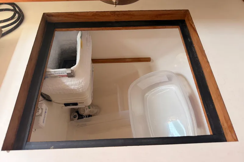 Slide: The Image of Storage compartment in a 1991 Caliber 33 boat, featuring insulated container and plastic bin. - 33