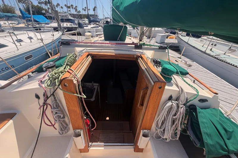 Slide: The Image of Sailboat deck view of 1991 Caliber 33, featuring ropes and open cabin entrance. - 26