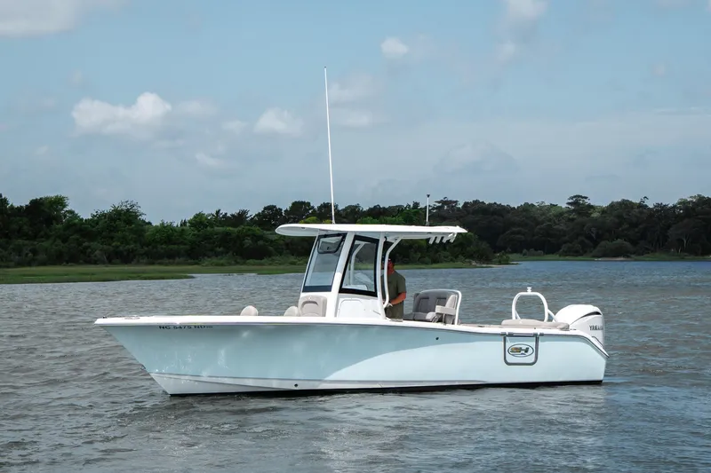 The Image of 2024 Sea Hunt Ultra 255 SE boat on calm water, with lush green shoreline. - 1