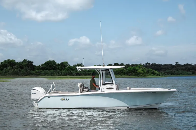 Slide: The Image of 2024 Sea Hunt Ultra 255 SE boat cruising on a calm lake under a clear sky. - 3