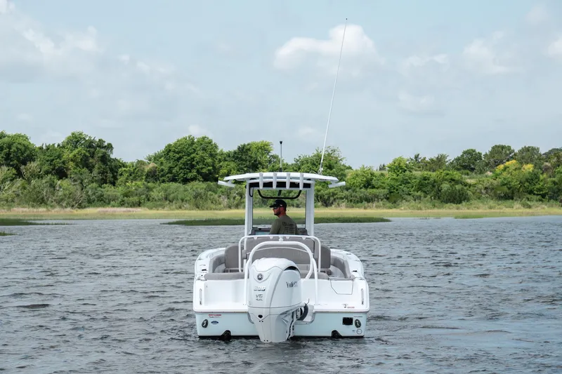 Slide: The Image of 2024 Sea Hunt Ultra 255 SE boat cruising on a serene lake with lush greenery. - 4