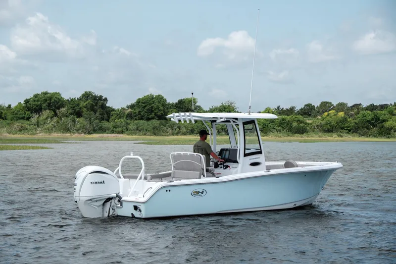 Slide: The Image of 2024 Sea Hunt Ultra 255 SE boat cruising on a calm lake with lush green shoreline. - 6