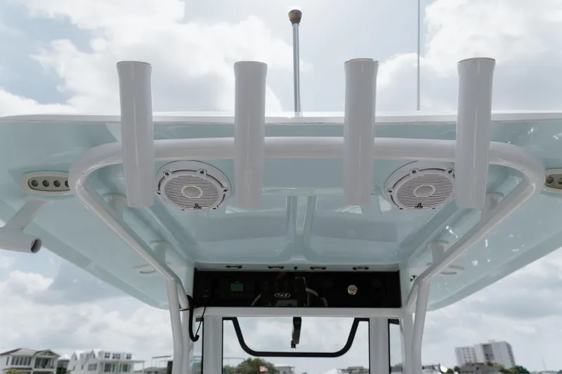 Slide: The Image of 2024 Sea Hunt Ultra 255 SE boat roof with rod holders and speakers under cloudy sky. - 9