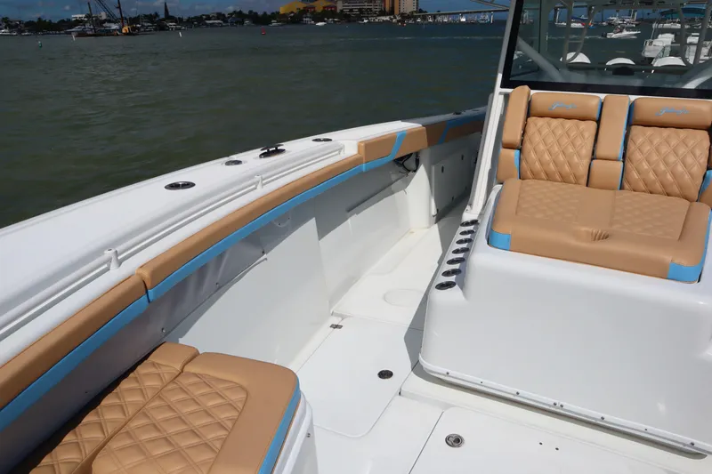 Slide: The Image of 2022 Yellowfin 42 Offshore boat interior with tan and blue seating, docked on calm water. - 18