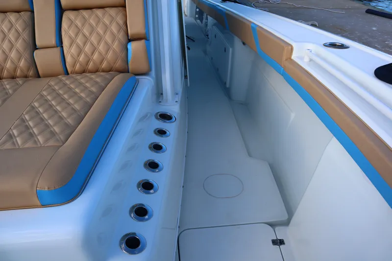 Slide: The Image of 2022 Yellowfin 42 Offshore boat interior with tan and blue seating, rod holders, and deck view. - 46