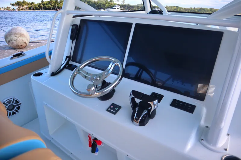 Slide: The Image of 2022 Yellowfin 42 Offshore boat dashboard with dual screens and steering wheel. - 52