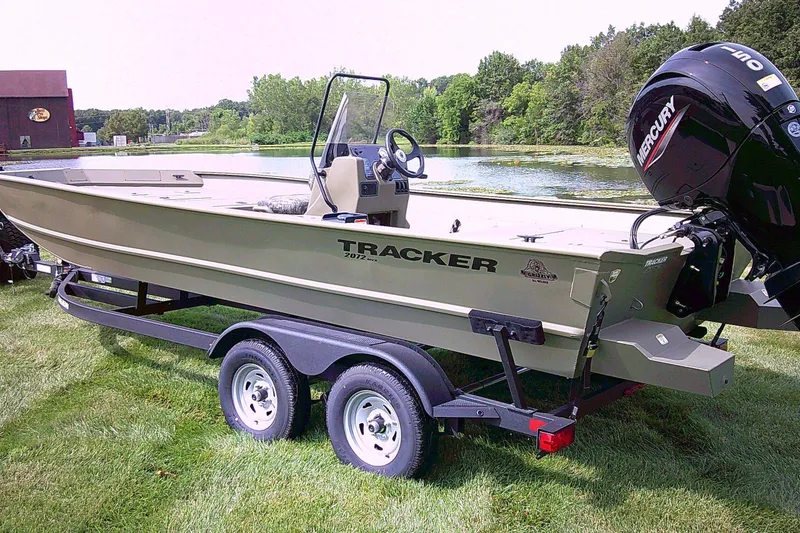 The Image of 2026 Tracker Grizzly 2072 CC boat on trailer by a scenic lake. - 0