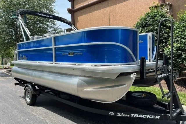 Slide: The Image of 2026 Sun Tracker Party Barge 18 DLX pontoon boat on trailer, blue exterior. - 1