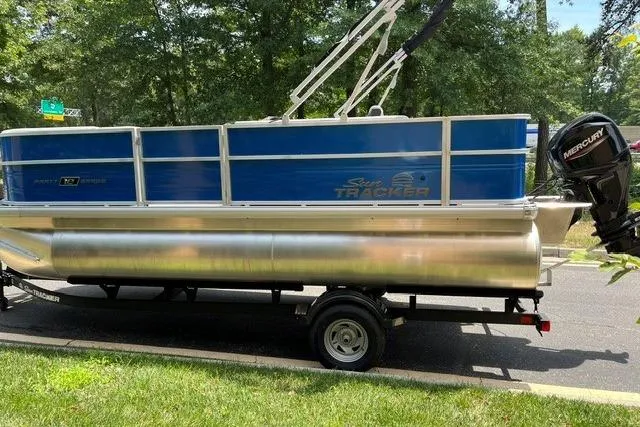 Slide: The Image of 2026 Sun Tracker Party Barge 18 DLX pontoon boat on trailer, parked outdoors. - 2