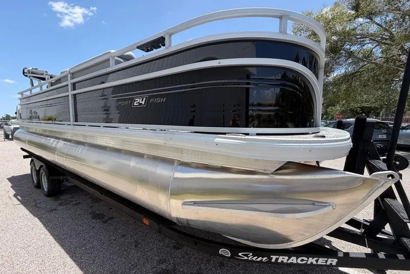 Slide: The Image of 2026 Sun Tracker Sportfish 24 XP3 pontoon boat on trailer, side view under sunny sky. - 7